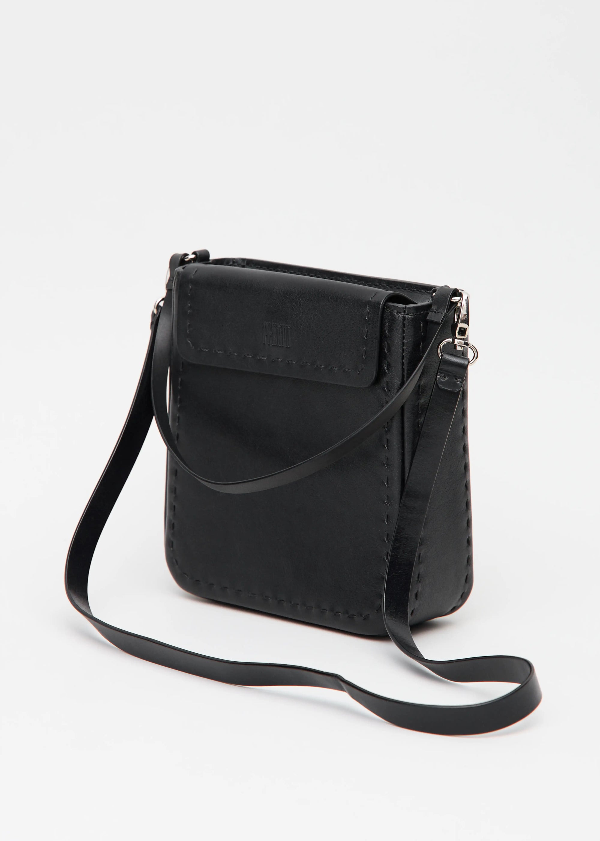 Side view of the Philini Saphira Purse in black aniline leather, compact rectangular silhouette with hand-stitched accents, smooth half-lap flap, and versatile leather and chain handles. Handmade black leather evening bag.