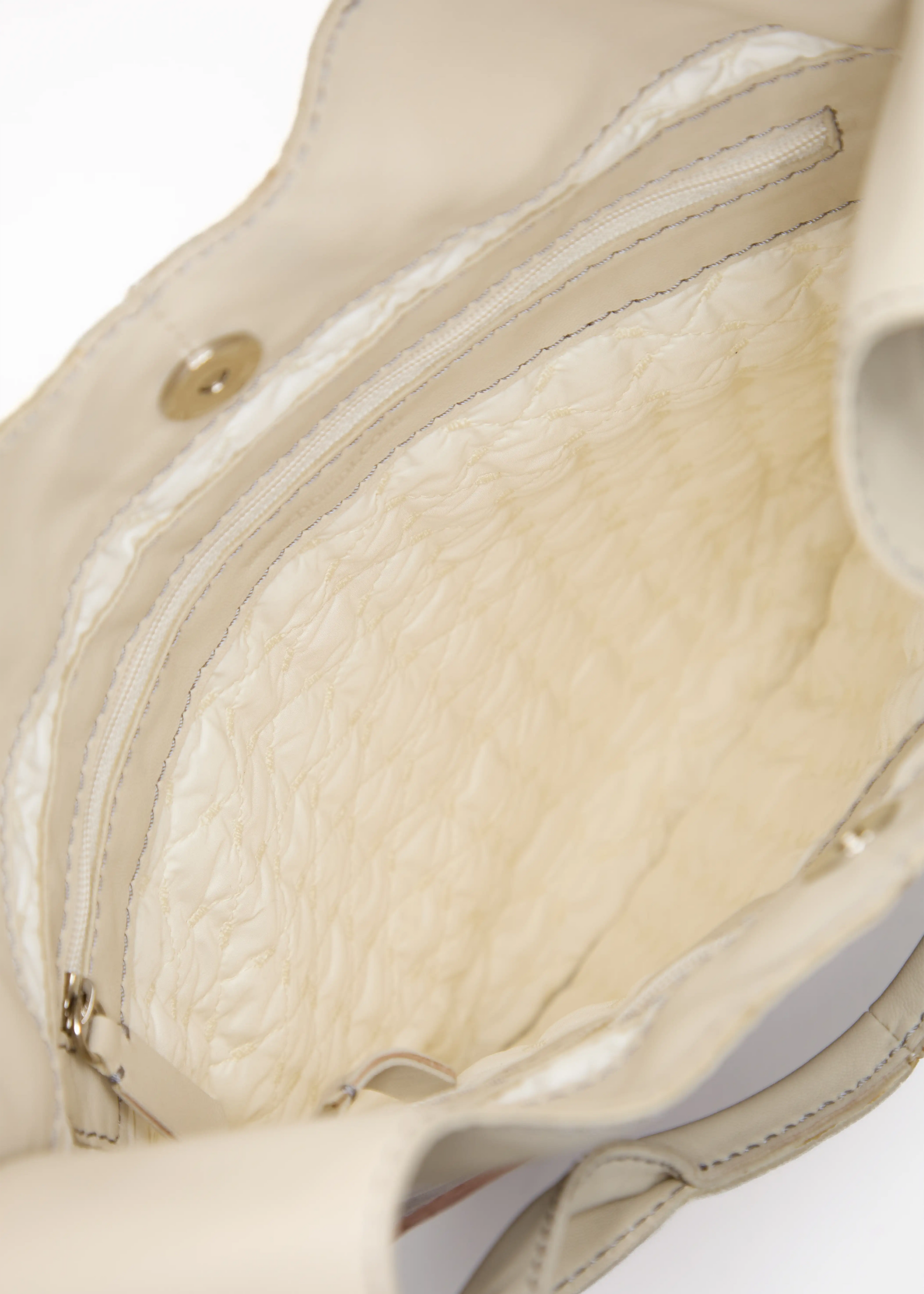 Inside view of the Philini Semfira Hobo Bag in cognac aniline leather, featuring stitched vanilla lining, dual deep zippered compartments, and magnetic closure. Sustainably made leather handbag