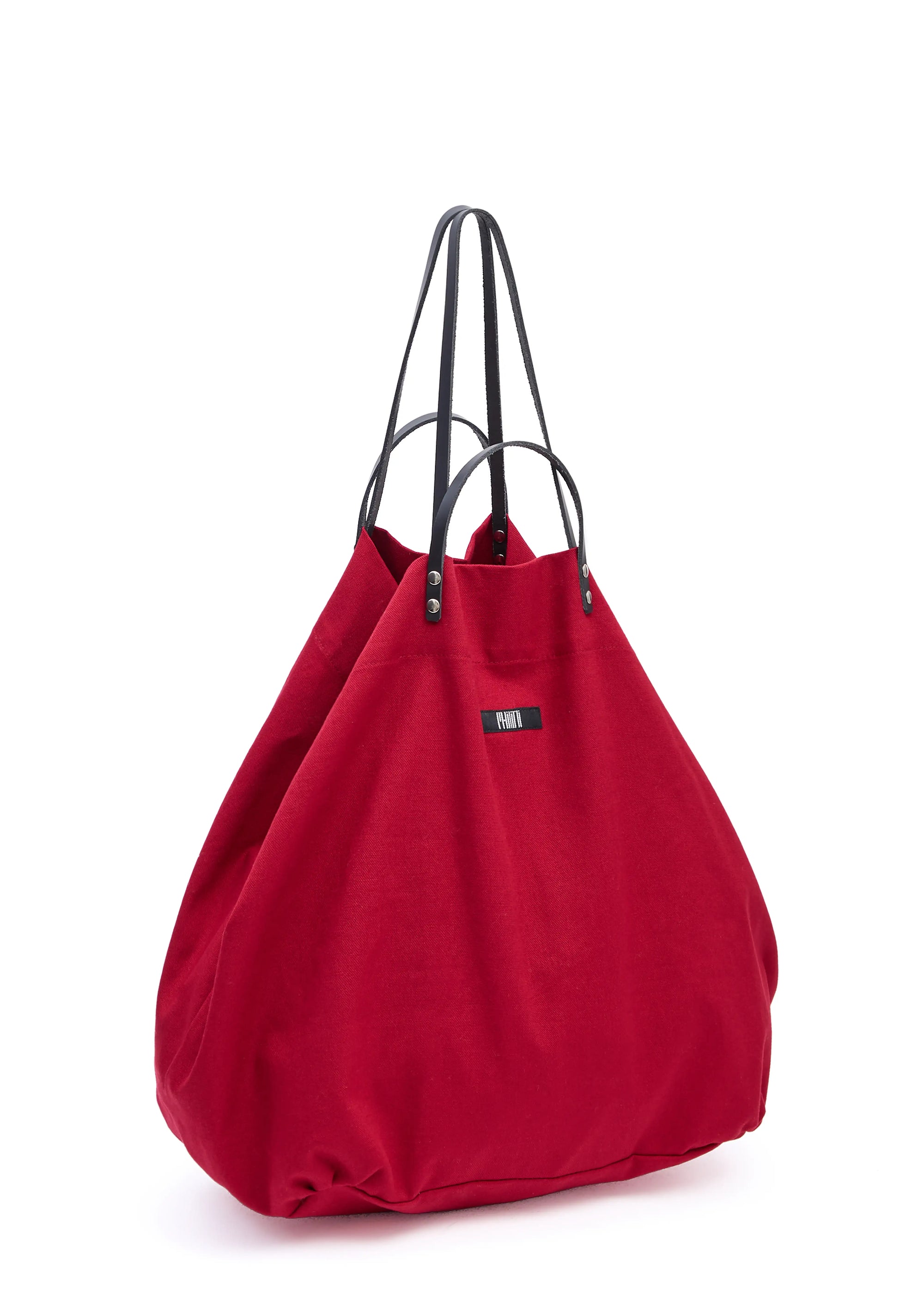 Side view of the Philini Red Shopper in bold cotton, featuring short and long calf leather handles with silver attachments, top button closure, and sewn fabric logo. Minimalist designer shopper 