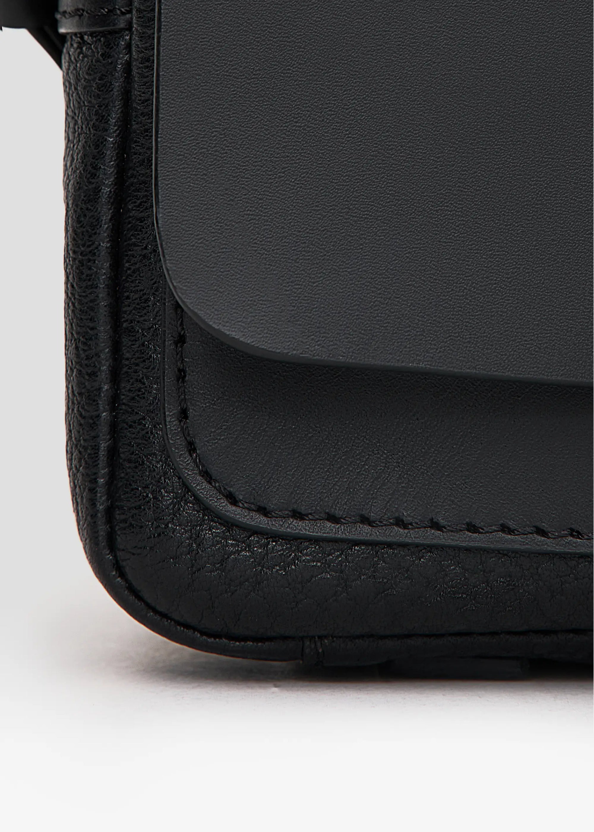 Detailed front view of the Philini Whitney Black Leather Bag, a rectangular handcrafted designer bag with a premium leather flap, silver push-button closure, adjustable strap, and protective leather pads. A sustainable and elegant accessory