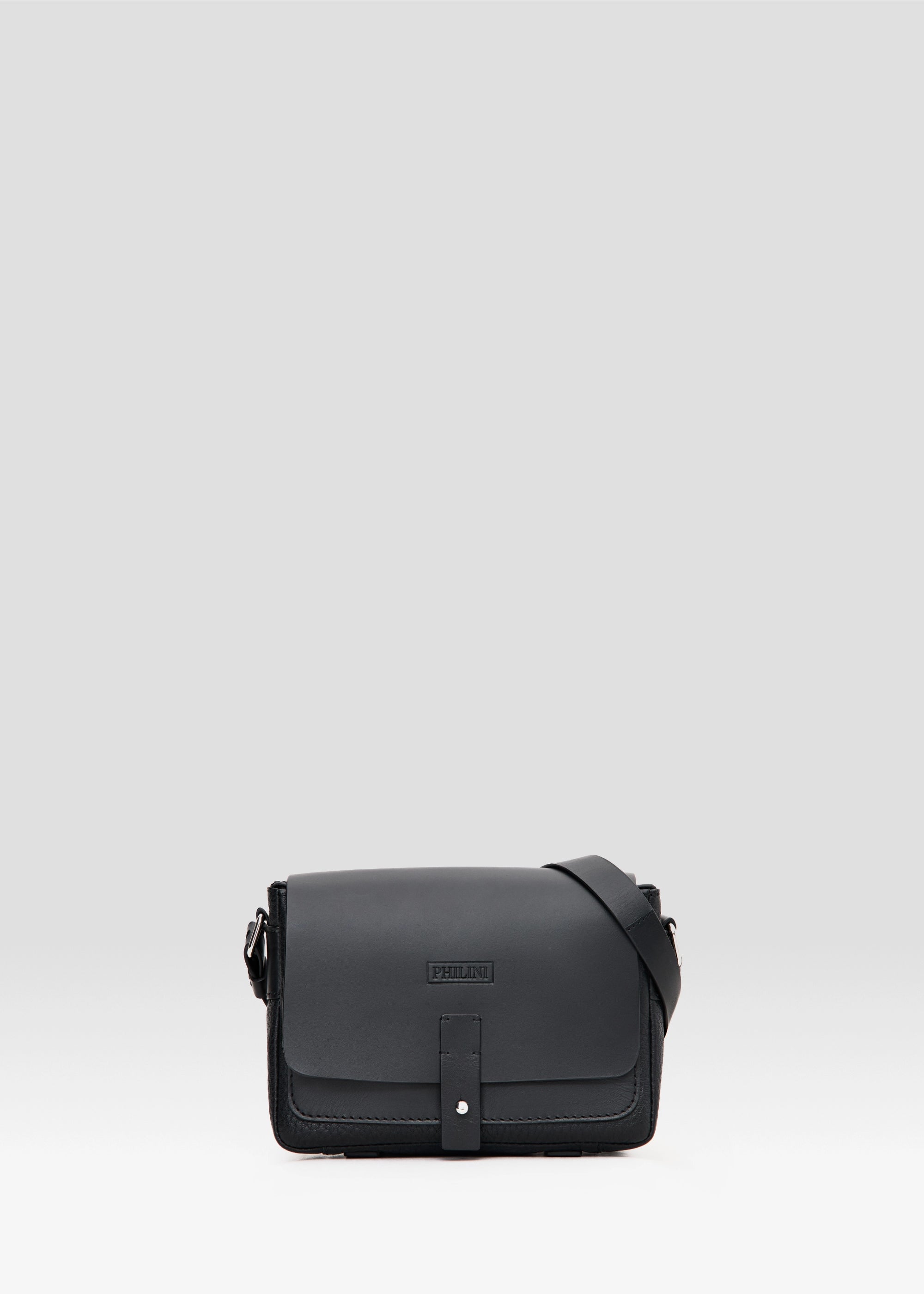  Front view of the Philini Whitney Black Leather Bag, a handcrafted designer bag with a rectangular shape, premium full-grain leather flap, silver push-button closure, and an adjustable strap with silver accents. German-designed and sustainable.