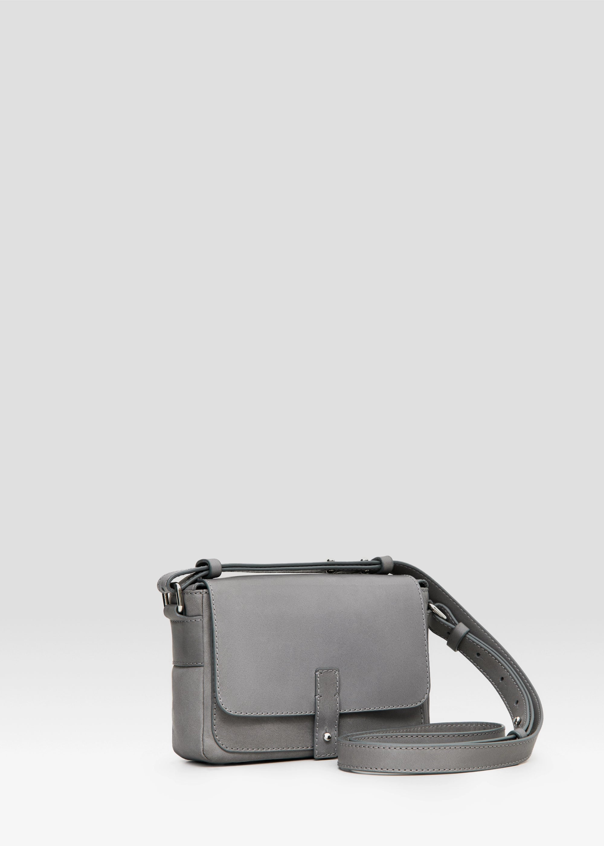 Side view of the grey Philini Whitney Mini Crossbody Bag in nappa leather with a rectangular shape, silver closure, and adjustable strap. A compact handcrafted bag for daily wear and polished style