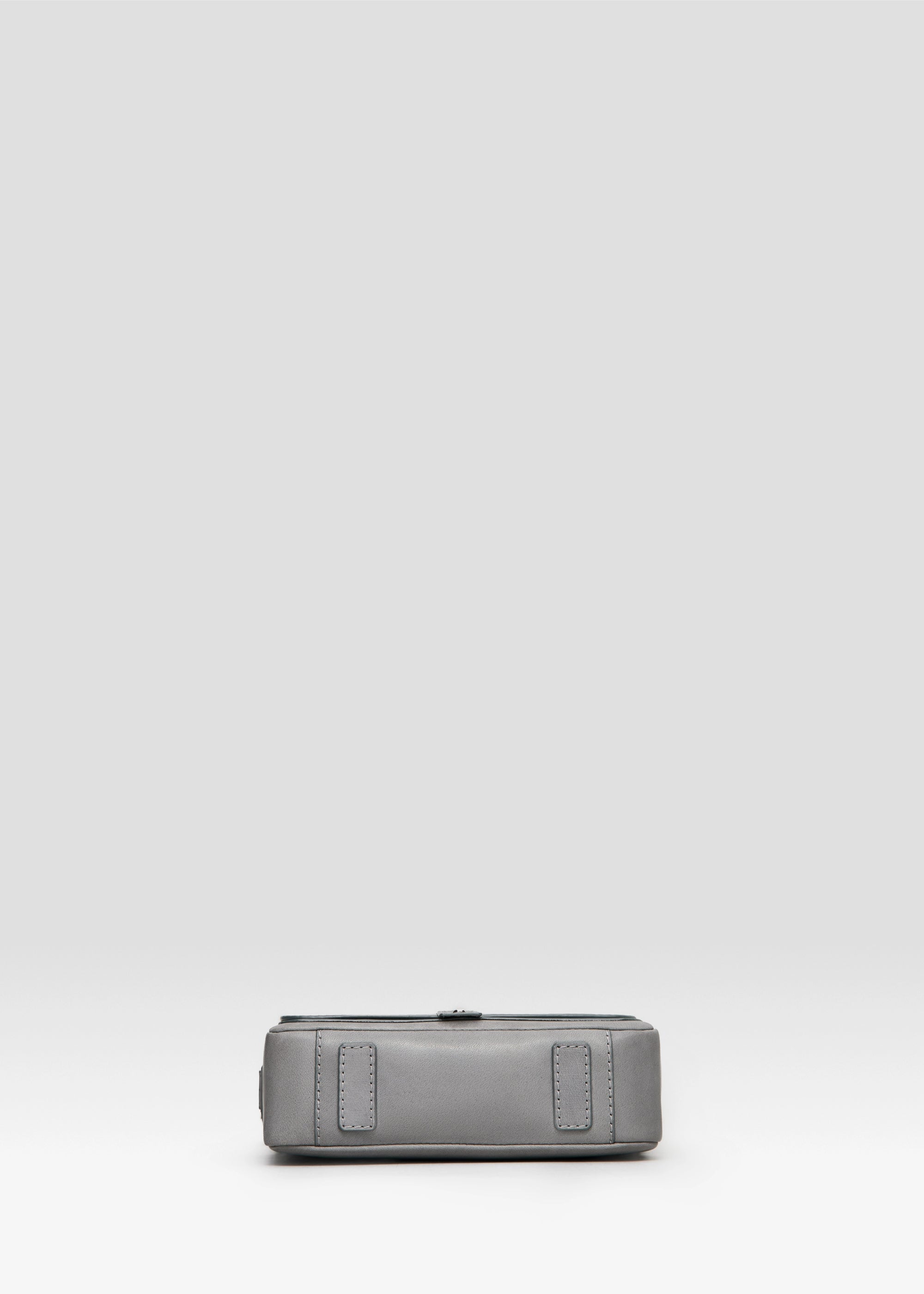 Bottom view of the grey Philini Whitney Mini Crossbody Bag in nappa leather, with leather pads and silver cufflink closure. A stylish mini leather crossbody and compact shoulder bag for everyday looks.