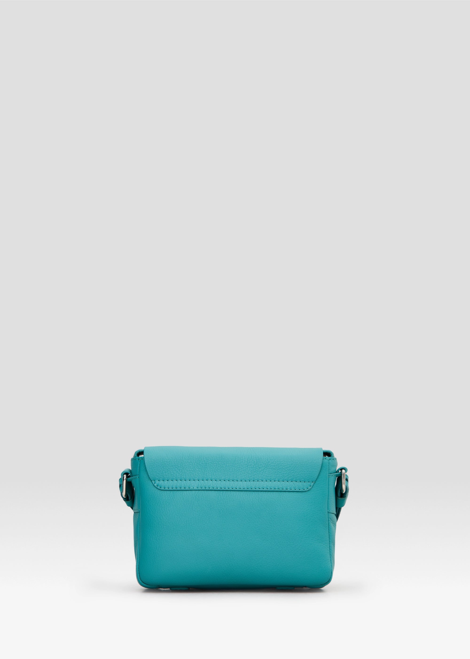Back view of the Philini Whitney Mini Crossbody Bag in turquoise Nappa leather, showcasing the vertical rectangle shape, adjustable leather strap with silver hardware, and secure strap attachment. A handcrafted mini bag is a luxury leather crossbody.