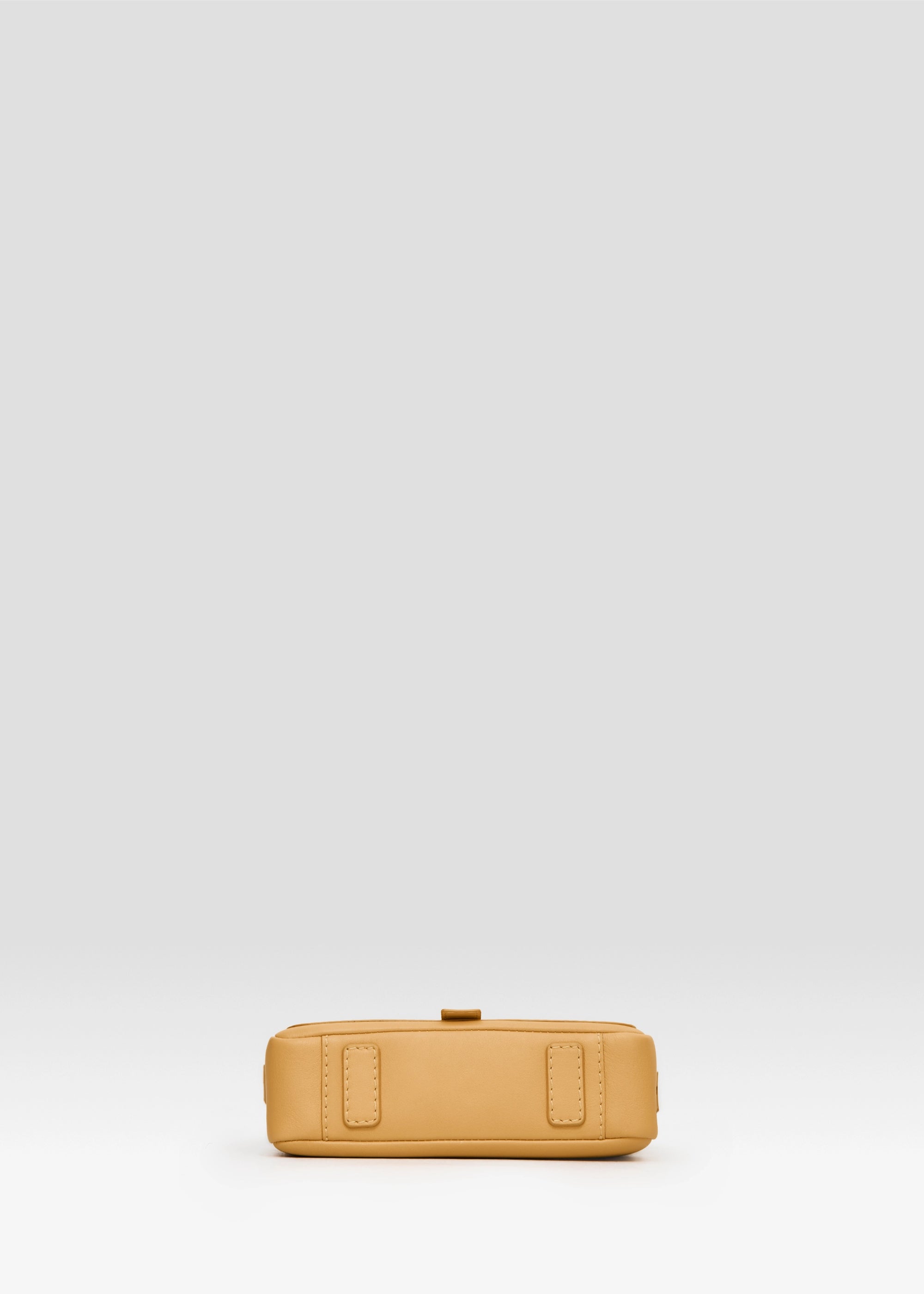 Bottom view of the Philini Whitney Mini Crossbody Bag in yellow nappa leather, featuring two leather pads as protective feet. The crossbody bag is a handcrafted mini purse