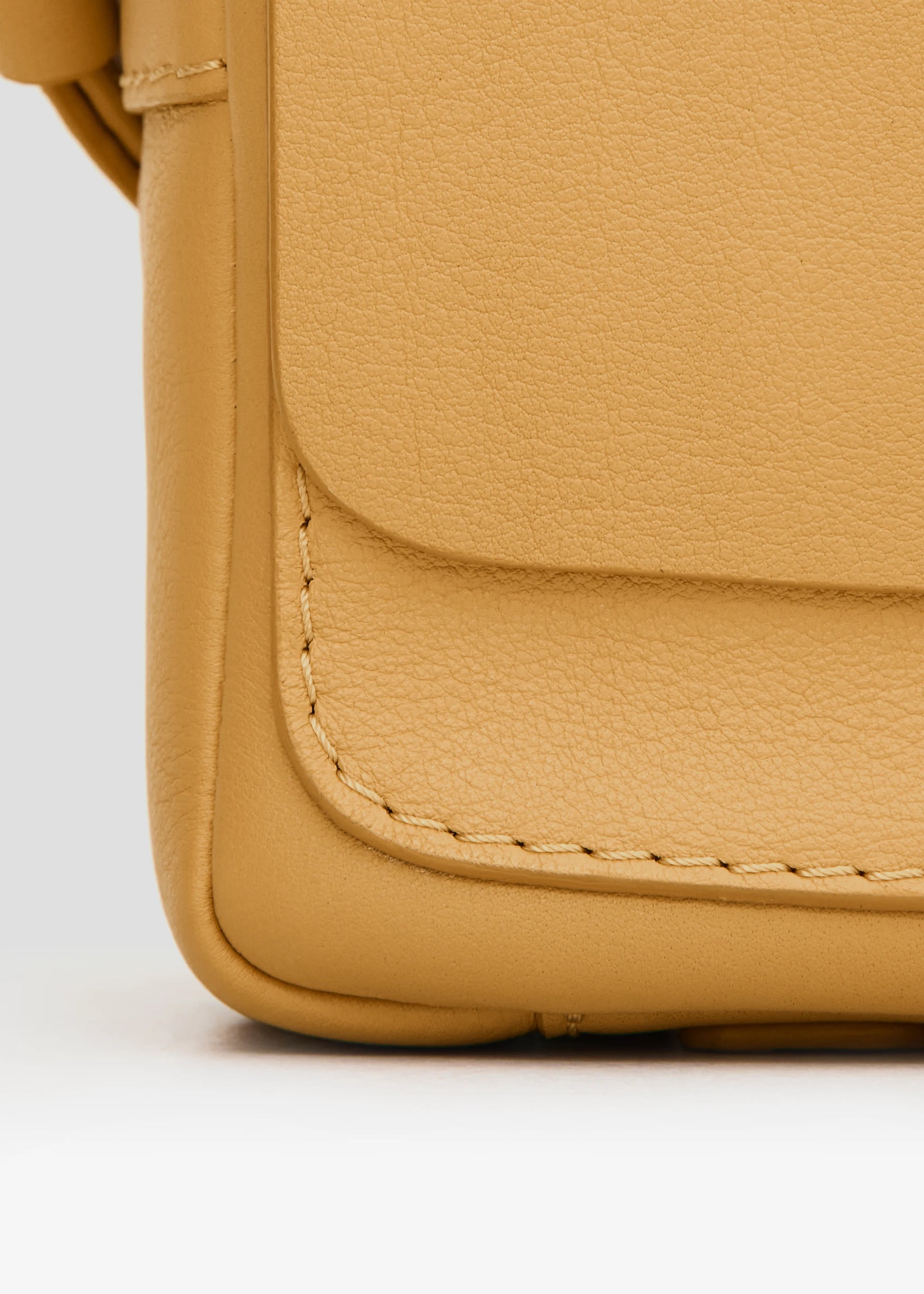 Close front view of the Philini Whitney Mini Crossbody Bag in yellow nappa leather, highlighting its natural leather texture, hand-stitched details, front flap with silver cufflink closure. The handcrafted mini designer handbag