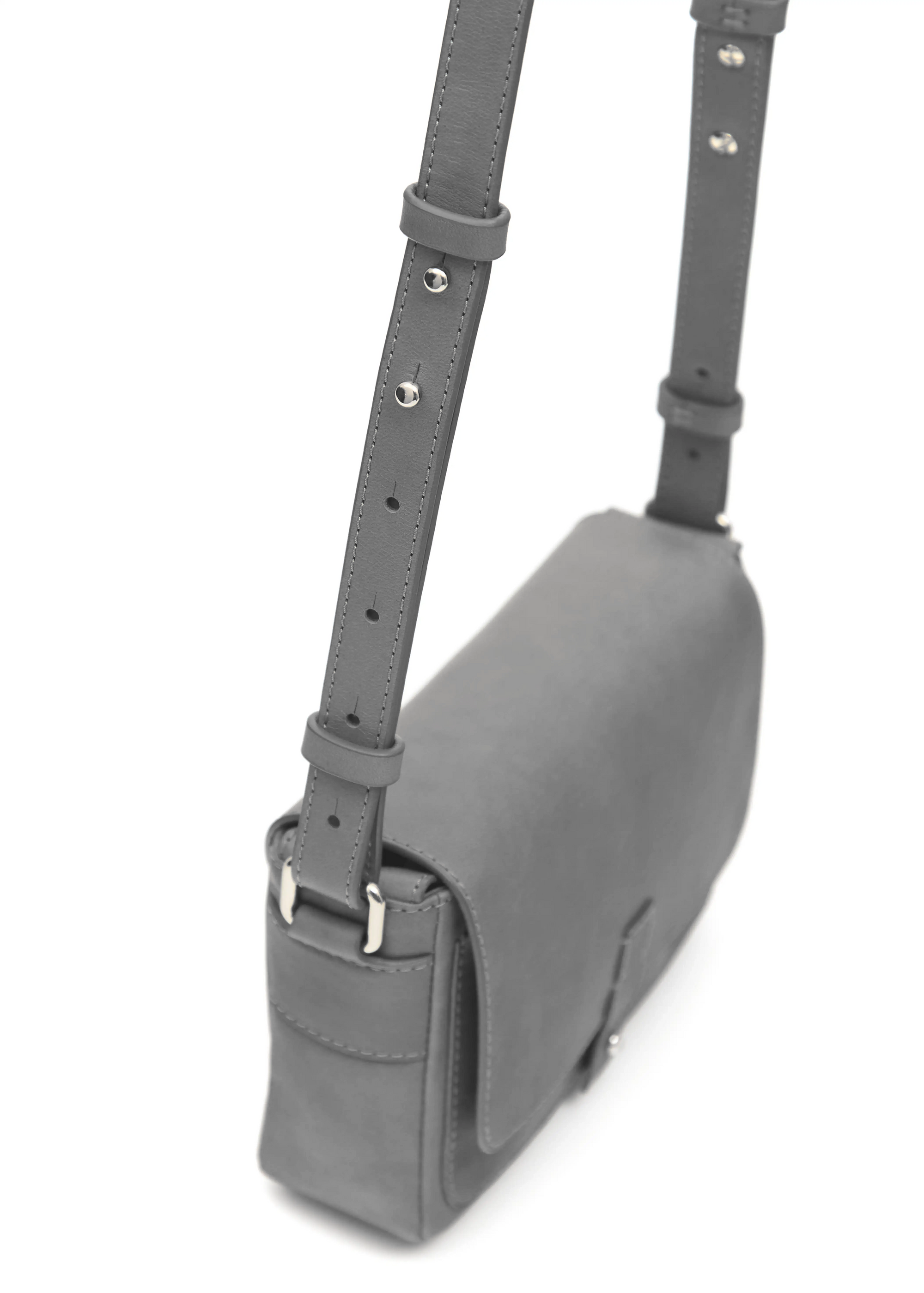 Close side view of the grey Philini Whitney Mini Crossbody Bag in nappa leather, featuring a vertical rectangle shape, silver cufflink flap, adjustable strap, and hand-stitched details. A compact, handcrafted luxury leather crossbody for sustainable style and everyday elegance.