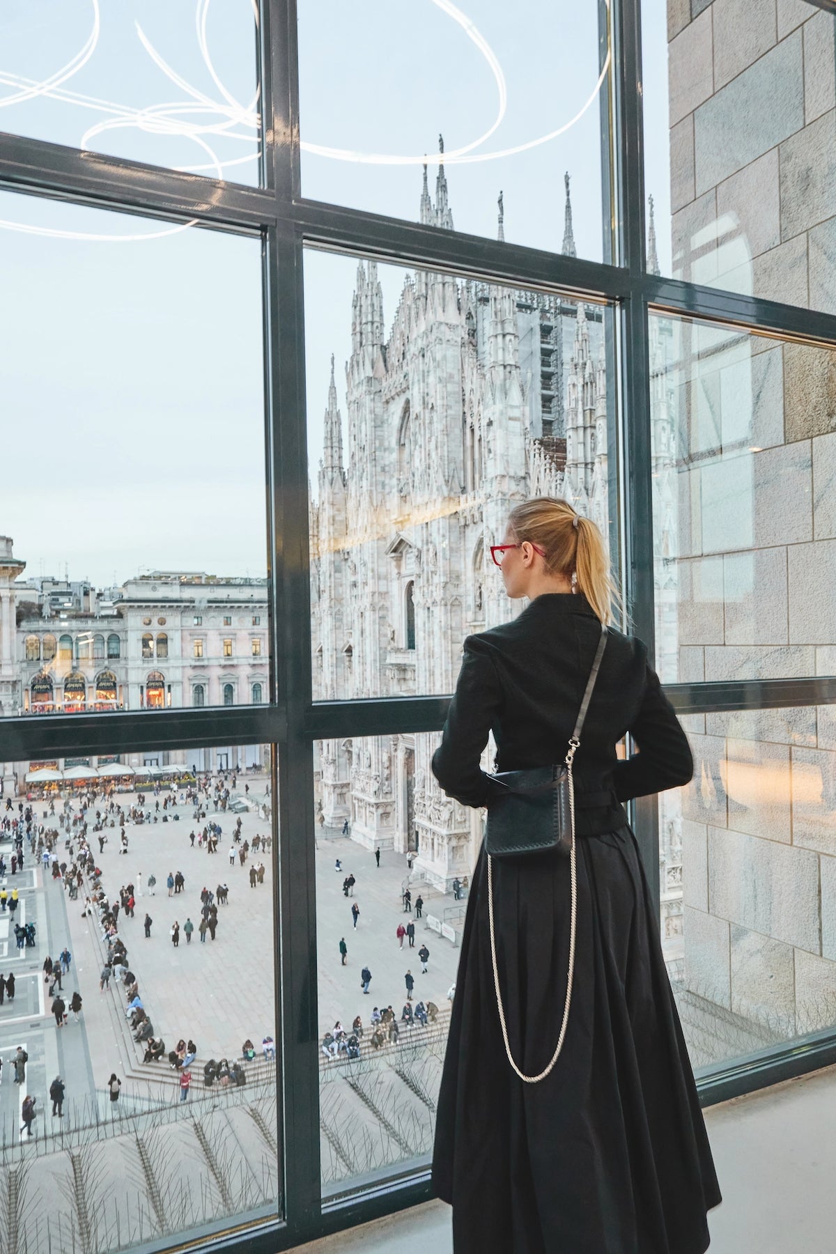 Woman wearing a black elegant PHILINI bag overlooking Milan Cathedral