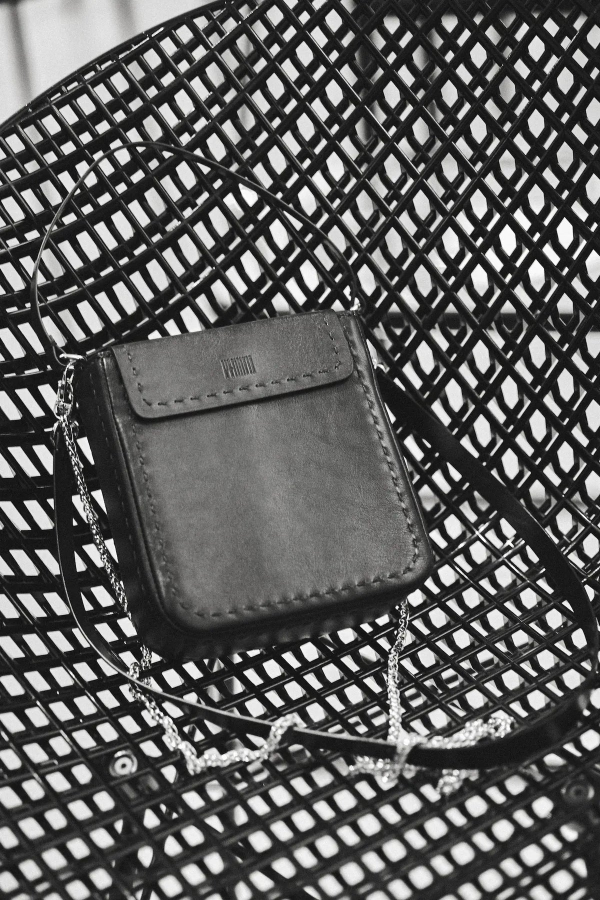 Black PHILINI leather elegant purse on a  modern metal chair in Milan