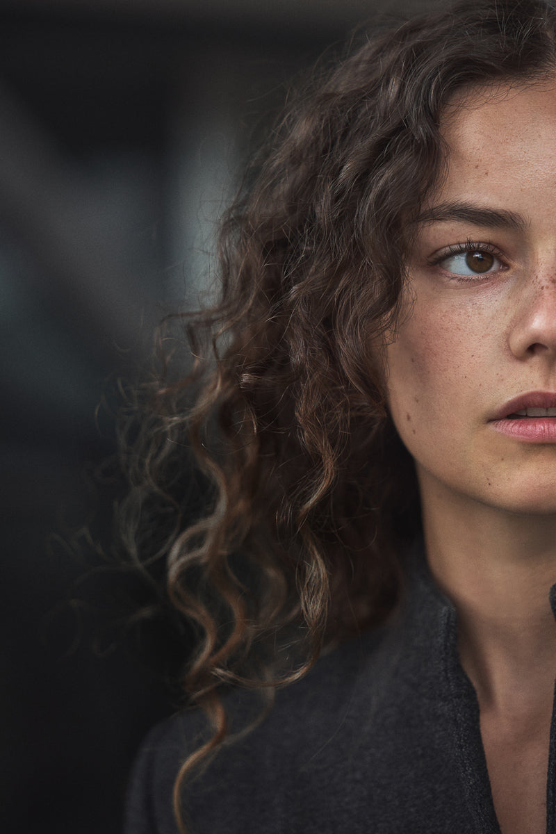 Close-up of a woman with curly hair against a dark background