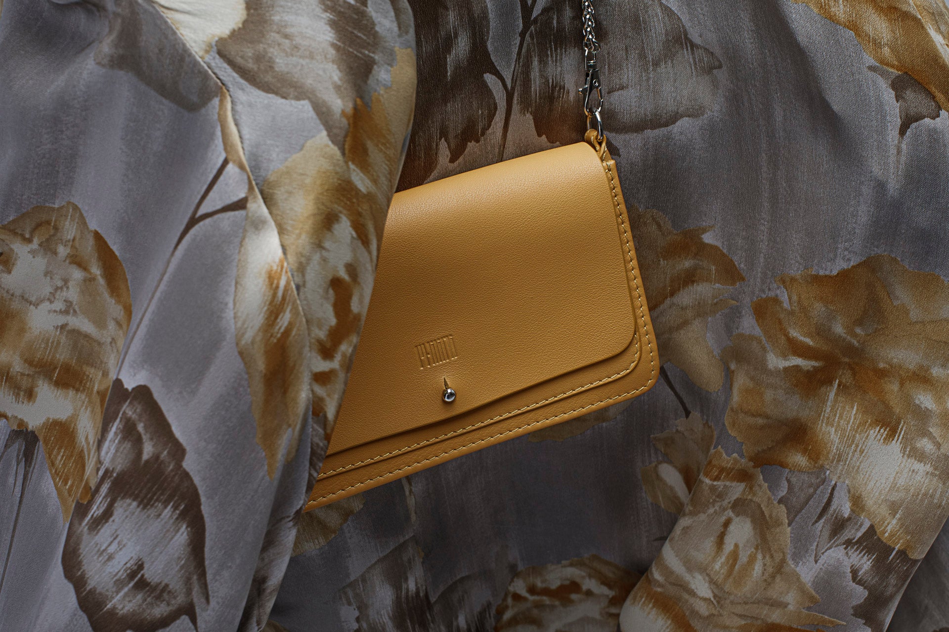 Woman wearing the yellow Philini Mihaela Wallet Bag in nappa leather as a crossbody with a silver chain strap, a compact handcrafted luxury bag in bright yellow