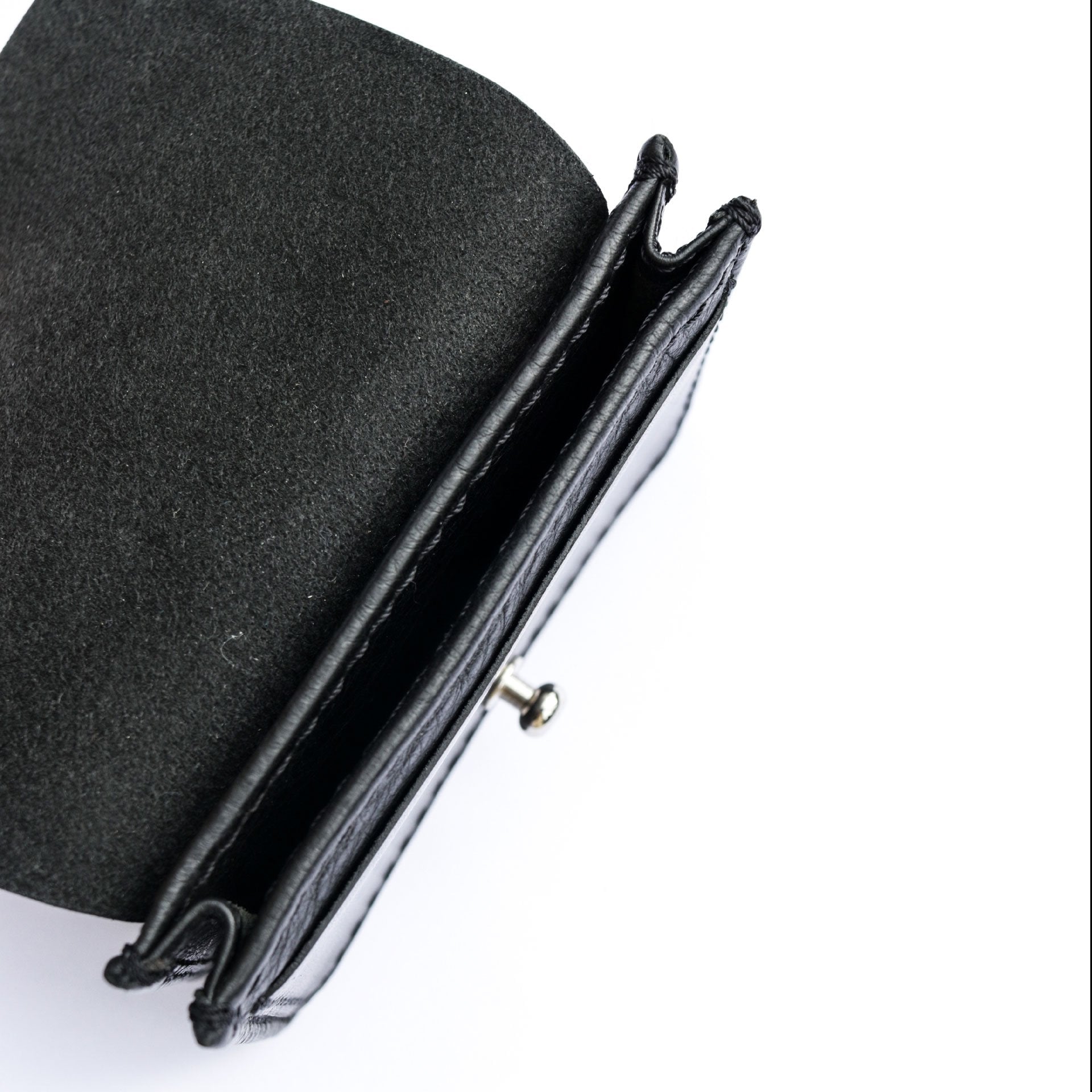 Top view of the Philini Lea Black Business Card Holder with the flap open, showing a silver cufflink closure, small exterior pocket, and interior card compartment in black buffalo leather. A handcrafted leather business accessory 